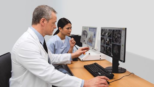 Photograph of a doctor and a female nurse looking at a monitor with a Leksell Gamma Knife delivery screen
